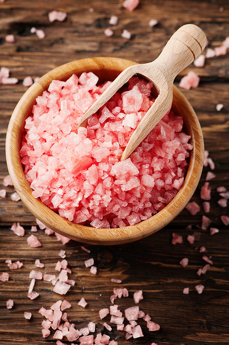 Coarse himalayan salt in bamboo bowl with bamboo spoon.