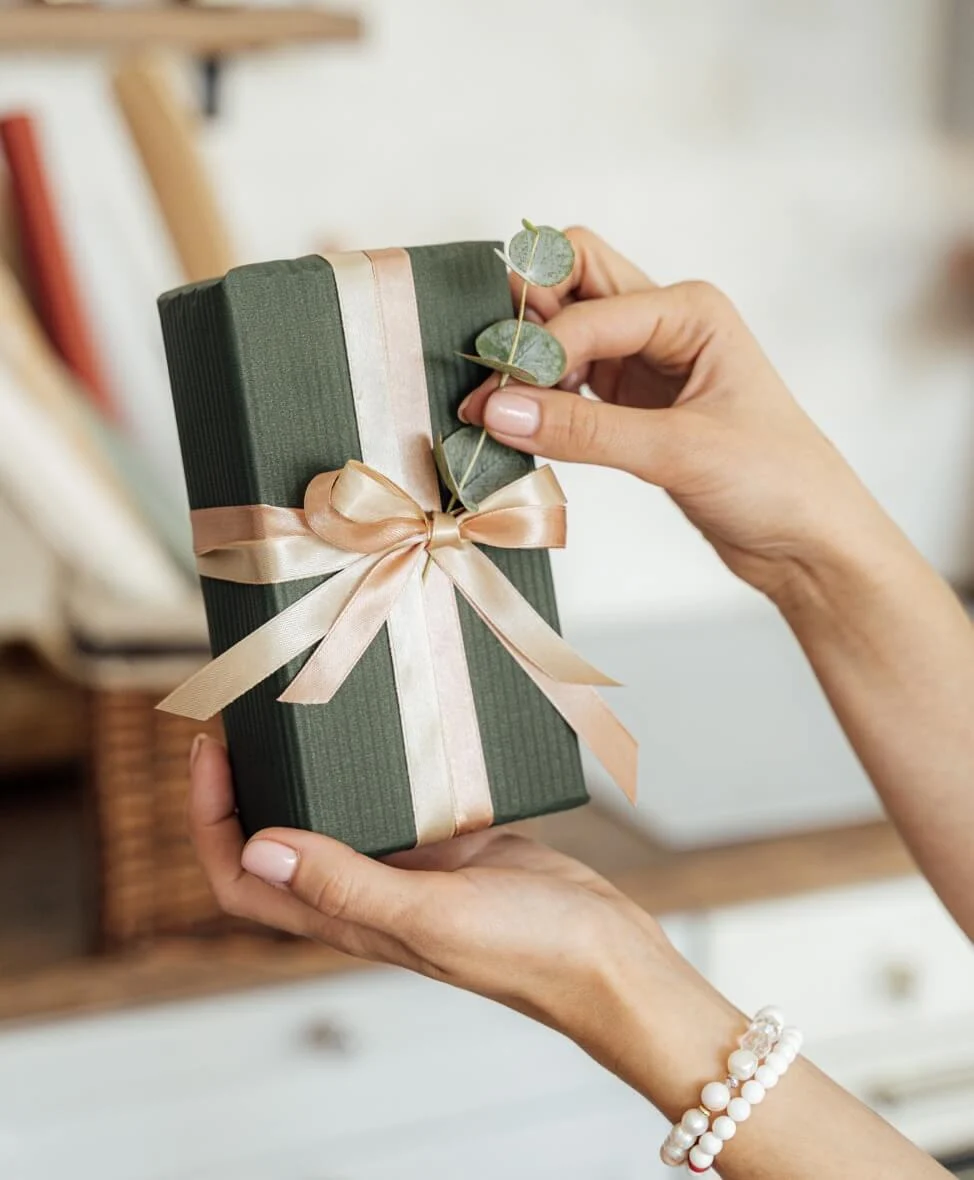 Image of a hand holding a gift box with a bow.